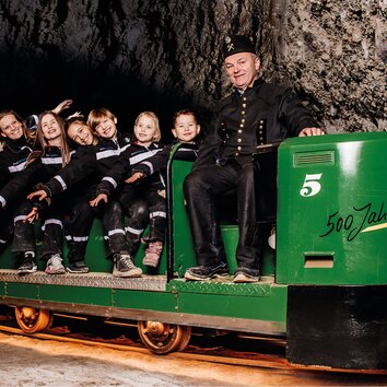 Bergführer fährt mit Besuchern auf der Grubenbahn 