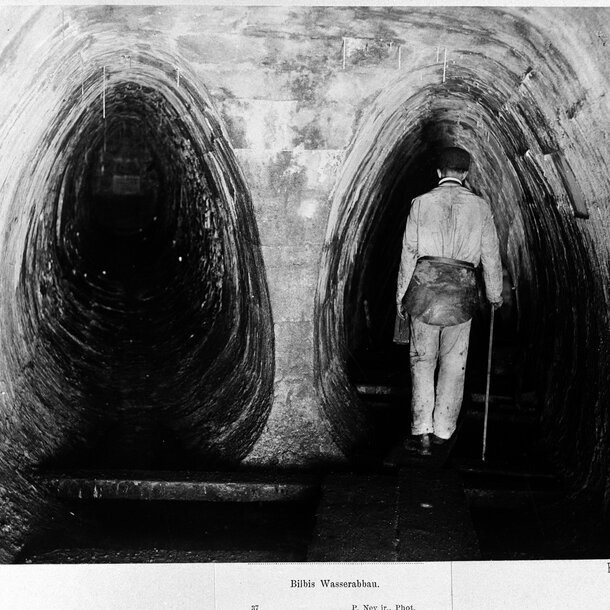 Schwarz-Weiß Fotografie eines Bergmanns mit Arschleder  von hinten