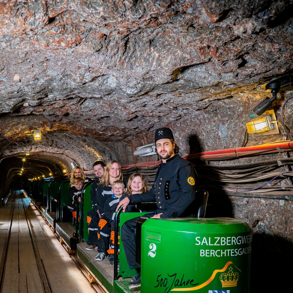 Führer mit Familie auf Grubenbahn im Salzbergwerk