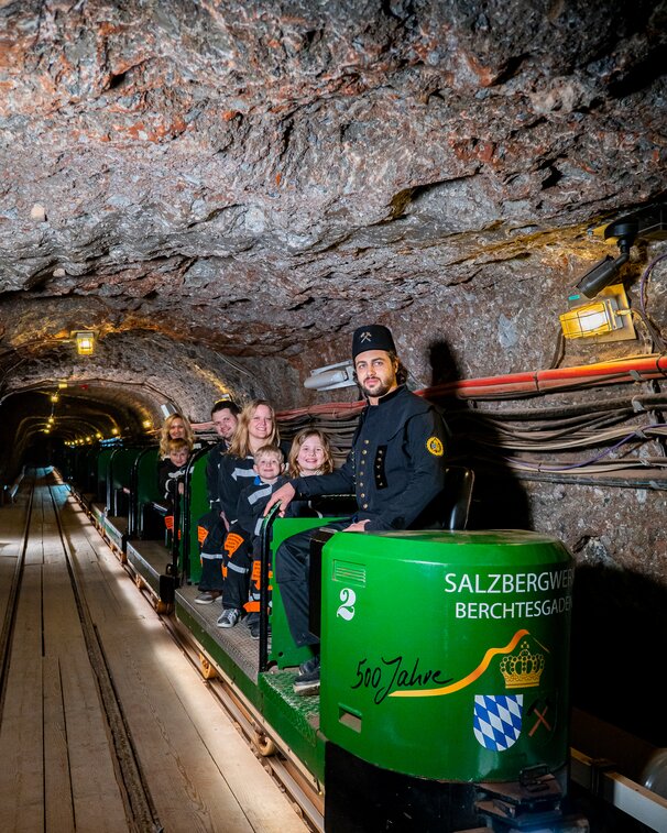 Führer mit Familie auf Grubenbahn im Salzbergwerk
