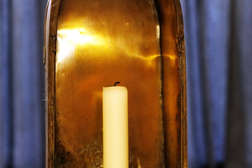 Eine kerzenbetriebene Grubenlampe mit Holzrahmen und reflektierendem, metallenem, Inneren. 
