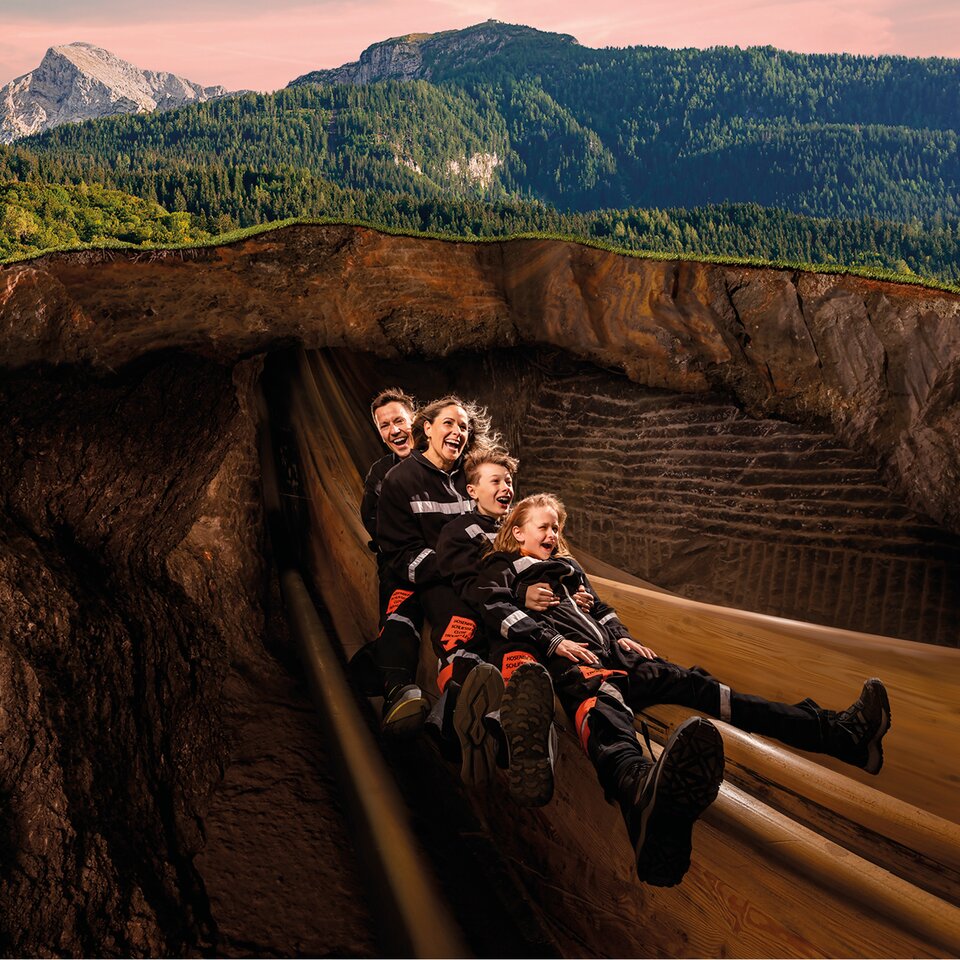 Familie rutscht auf der Holzrutsche im Inneren des Bergs.